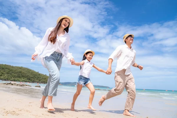 Famiglia felice che corre sulla spiaggia in una giornata di sole.